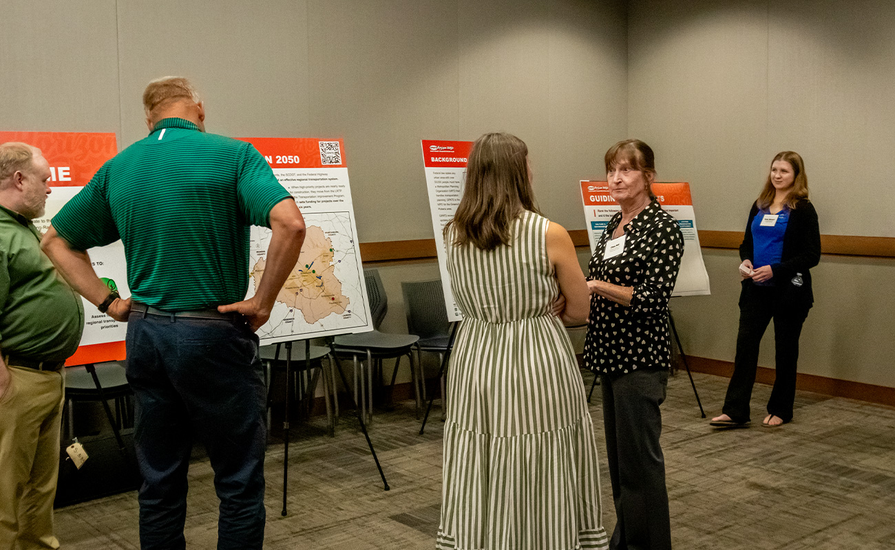 Travelers Rest meeting attendees talking with staff and reviewing meeting boards.